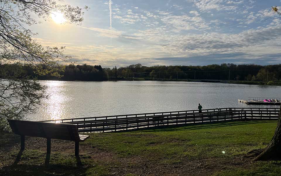 Sun over water with bench on hill